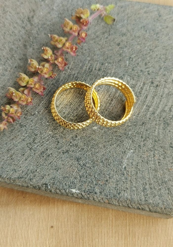 Traditional Three Layer Gold Tone Toe Rings on Gray Fabric with Floral Accents