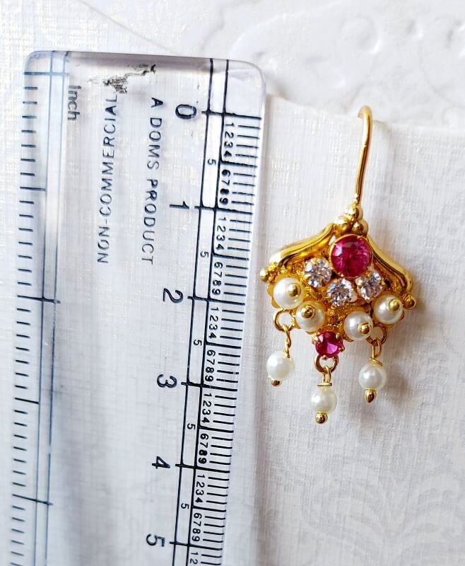 Elegant pearl and ruby jewelry against ruler background