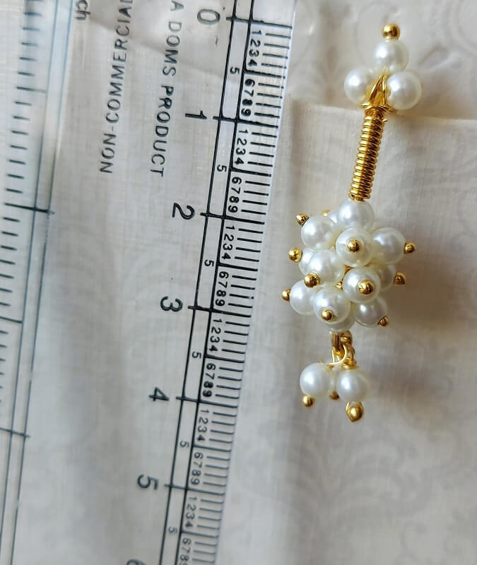 Elegant pearl and gold clustered earrings on ruler scale