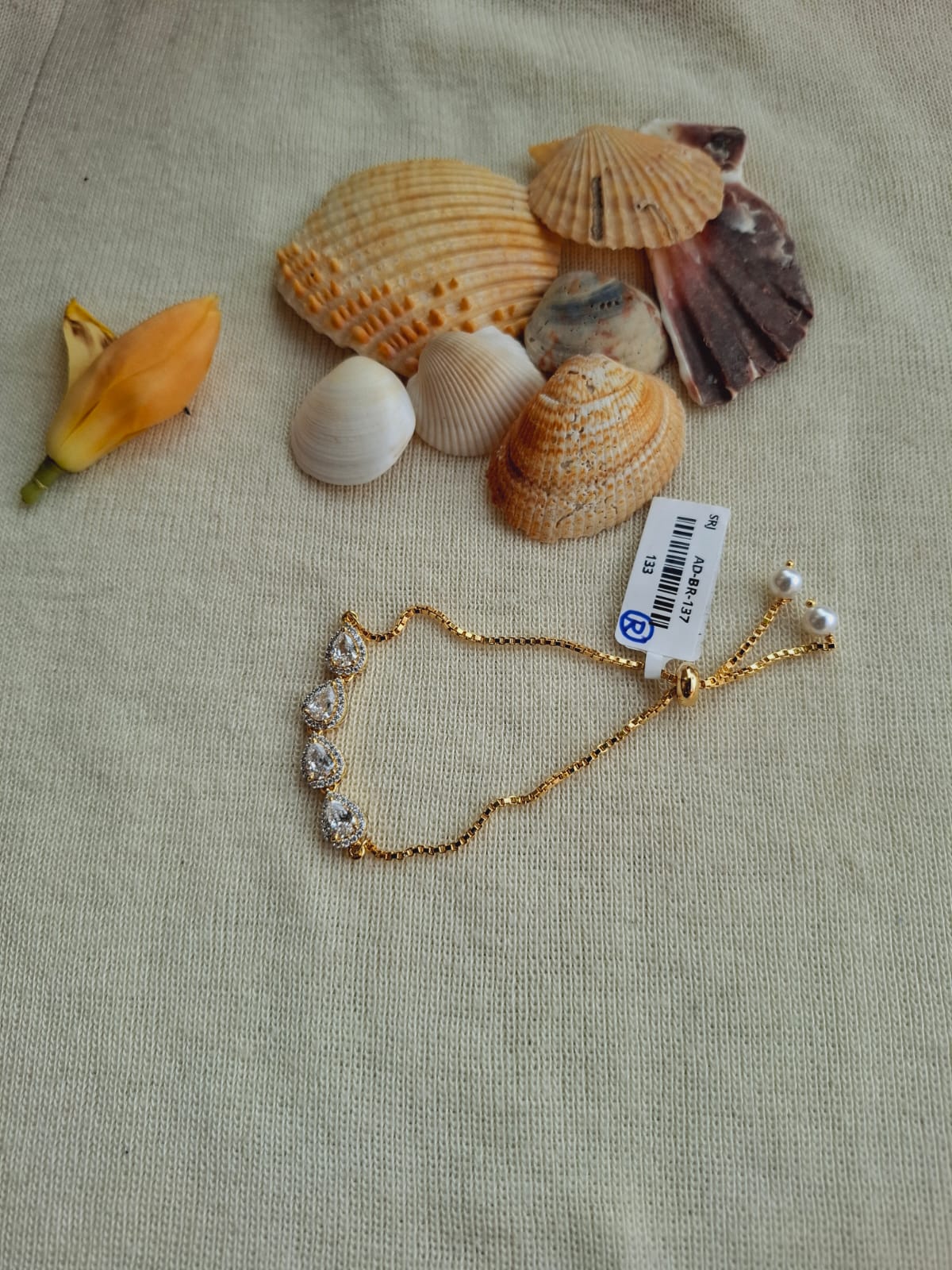 Elegant golden badam bracelet amid seashells on beige cloth