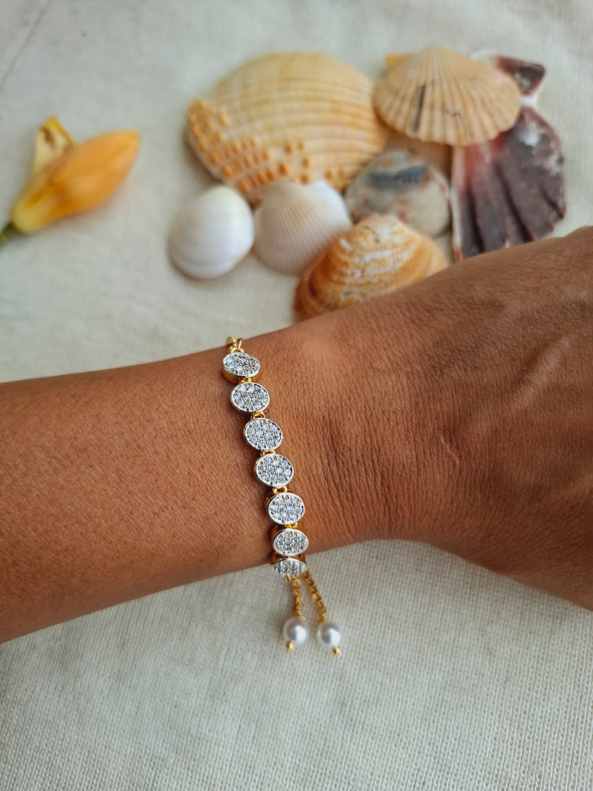 Elegant Gold Rhinestone Bracelet with Pearls on Arm Near Seashells