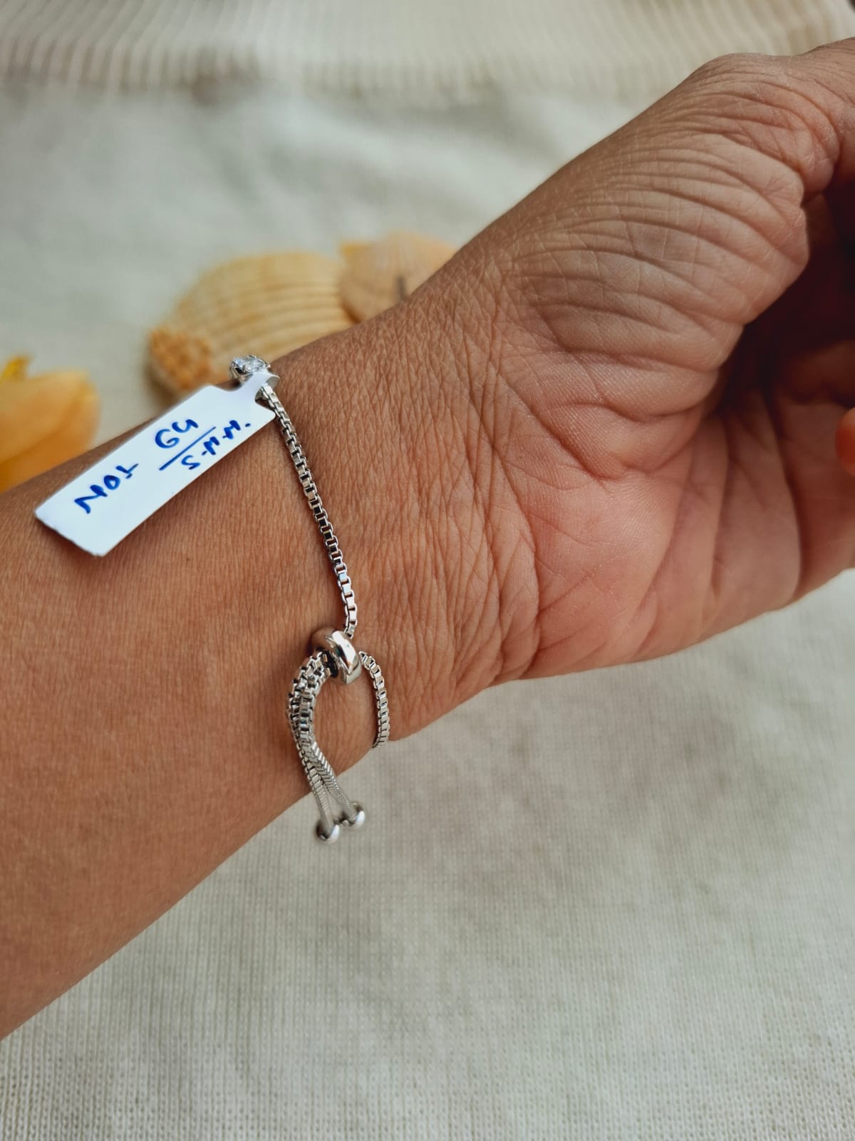 Adjustable silver bracelet with American diamond charm, showcased on a human hand against a blurred background in the Mugdha Jewellery Store.