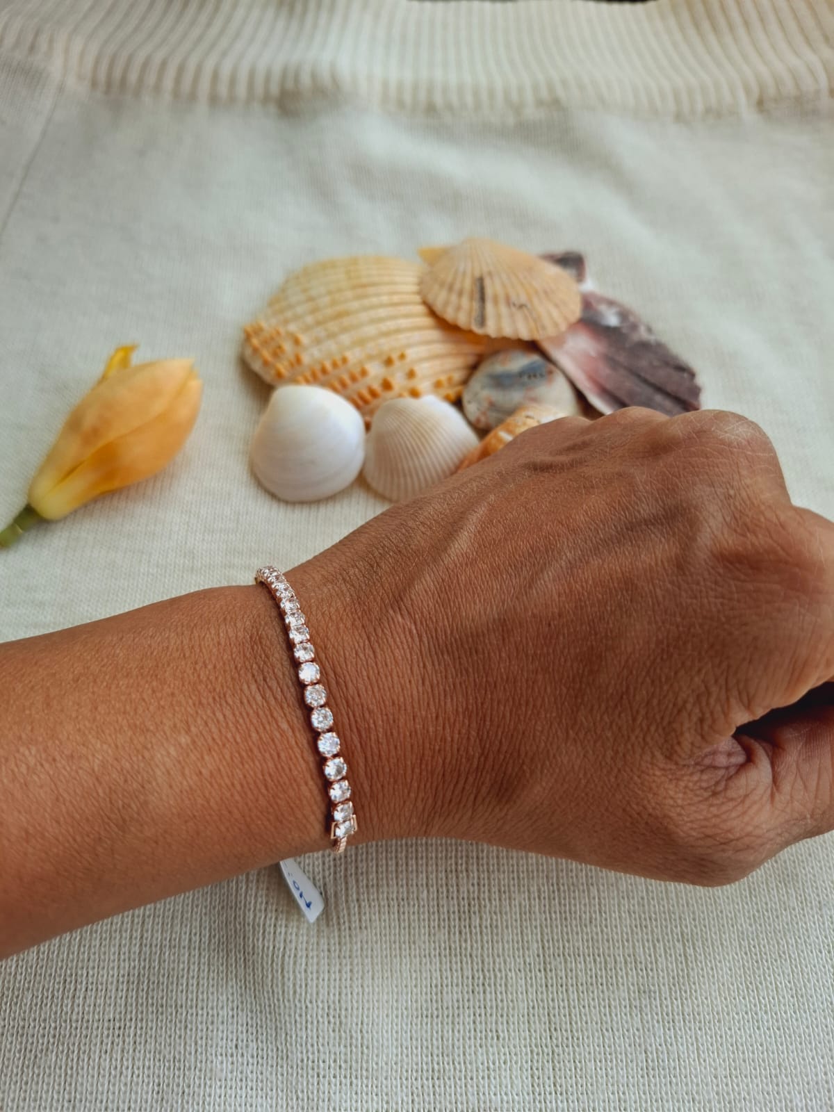 High-quality diamond and rose gold adjustable bracelet with seashell accessories displayed on knitted fabric background from Mugdha Jewellery Store.