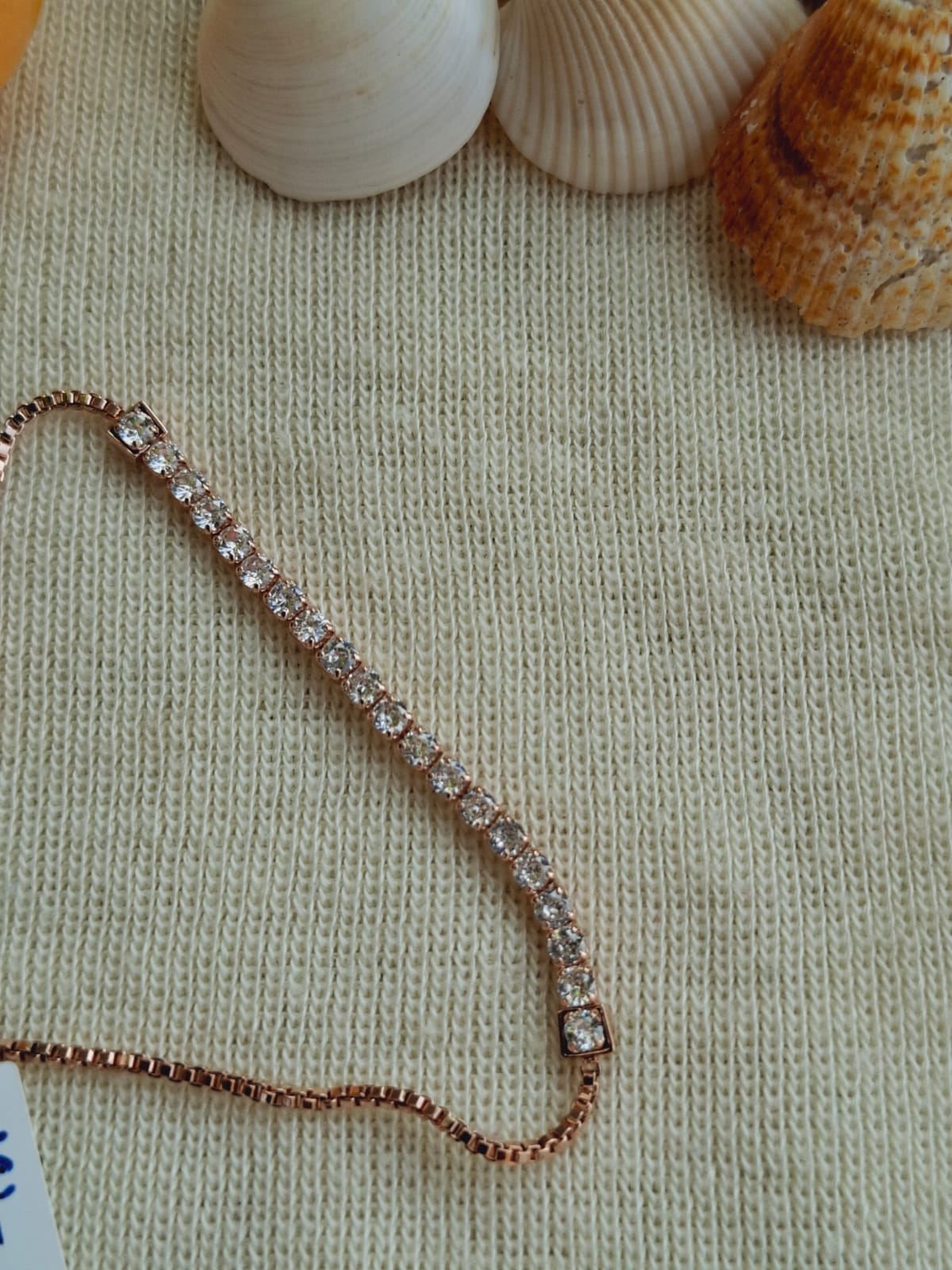 High Quality American Diamond Rose Gold Adjustable Bracelet on textured knit background with seashells