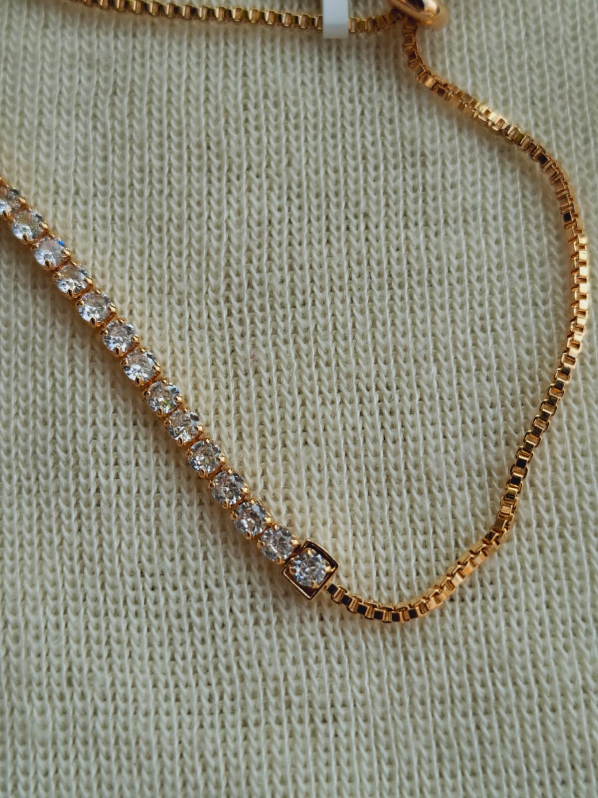 Elegant golden American diamond adjustable bracelet showcased on a textured fabric background.