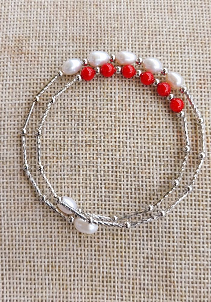Elegant pearl and coral designer bracelet from Mugdha Jewellery Store. Delicate silver-toned chain accented with lustrous pearls and vibrant red coral beads, creating a sophisticated and eye-catching accessory.