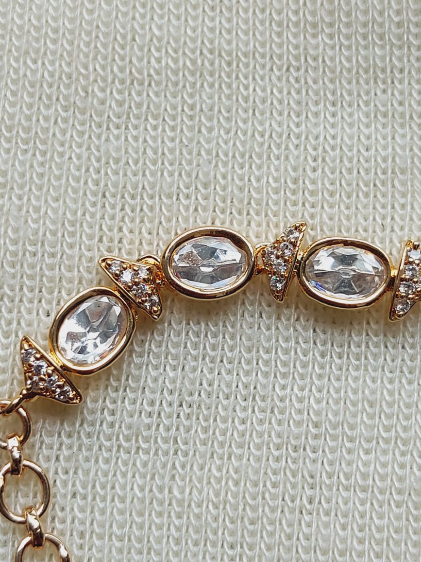 Elegant Oval Kundan Adjustable Bracelet
A beautifully crafted bracelet featuring oval-shaped kundan stones set in a golden-toned metal frame, accented with sparkling crystal embellishments, presented against a soft, knitted fabric background.