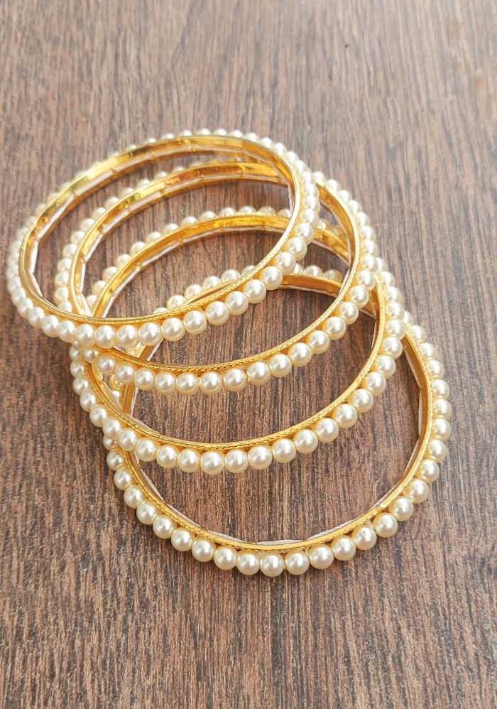 Elegant pearl bangles on wooden background