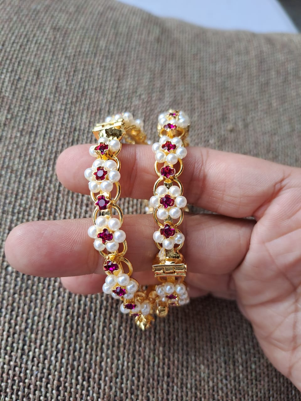 Traditional Kudi Tode earrings. Set of 2. Decorative floral motifs with pearls and red gemstones in a gold-toned metal frame.