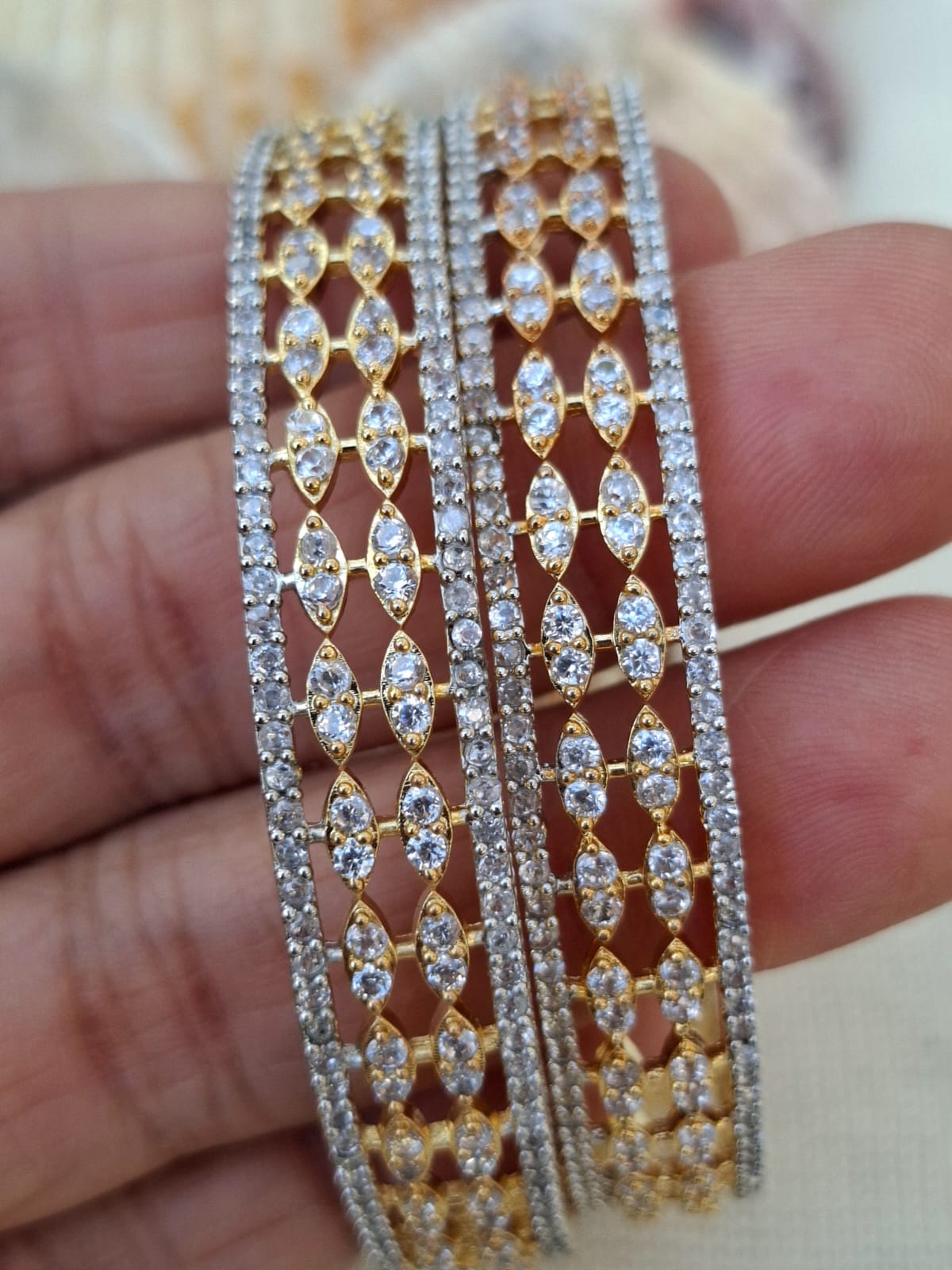 Elegant designer diamond bangles with intricate patterns. 2 high-quality American diamond bangles in a stylish gold setting. Showcasing a detailed lattice design accentuated by sparkling diamonds.