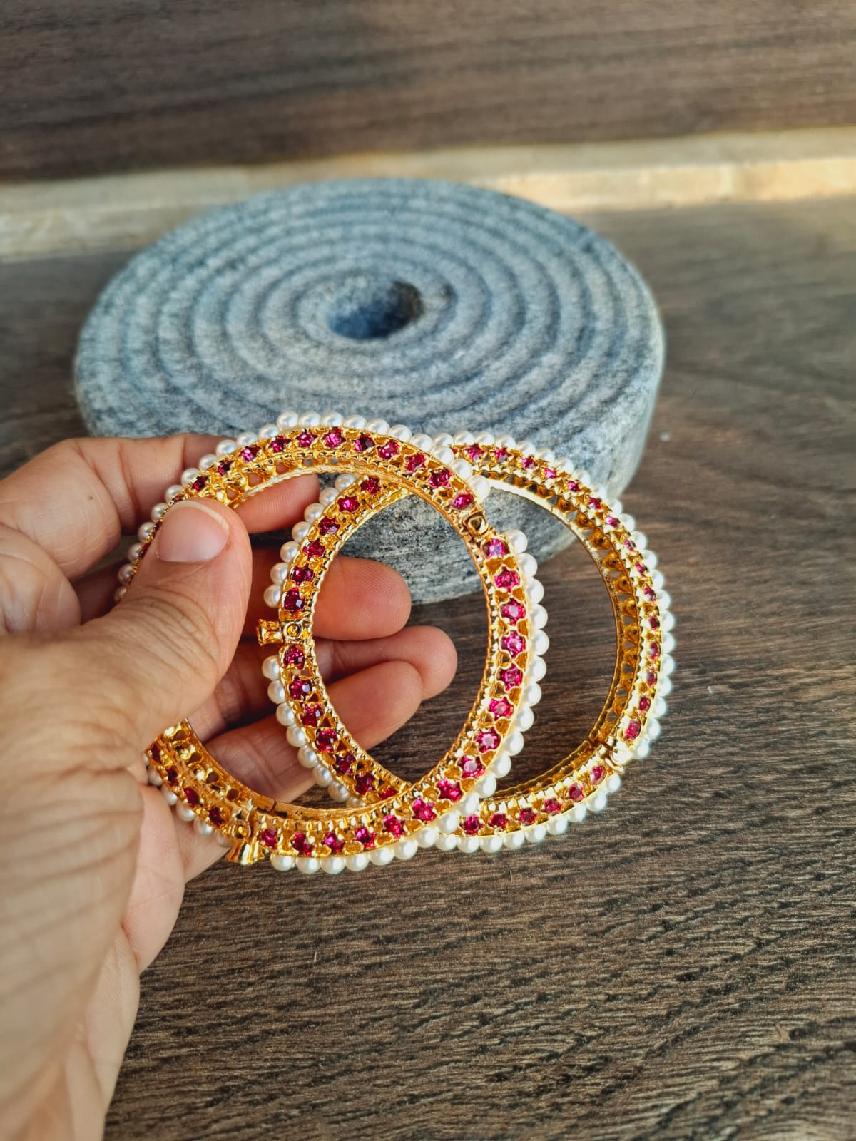 Traditional Pearl Tode Dark Pink Jewelry Set
Ornate gold-toned rings adorned with vibrant red and yellow jewels, placed on a gray textile background.