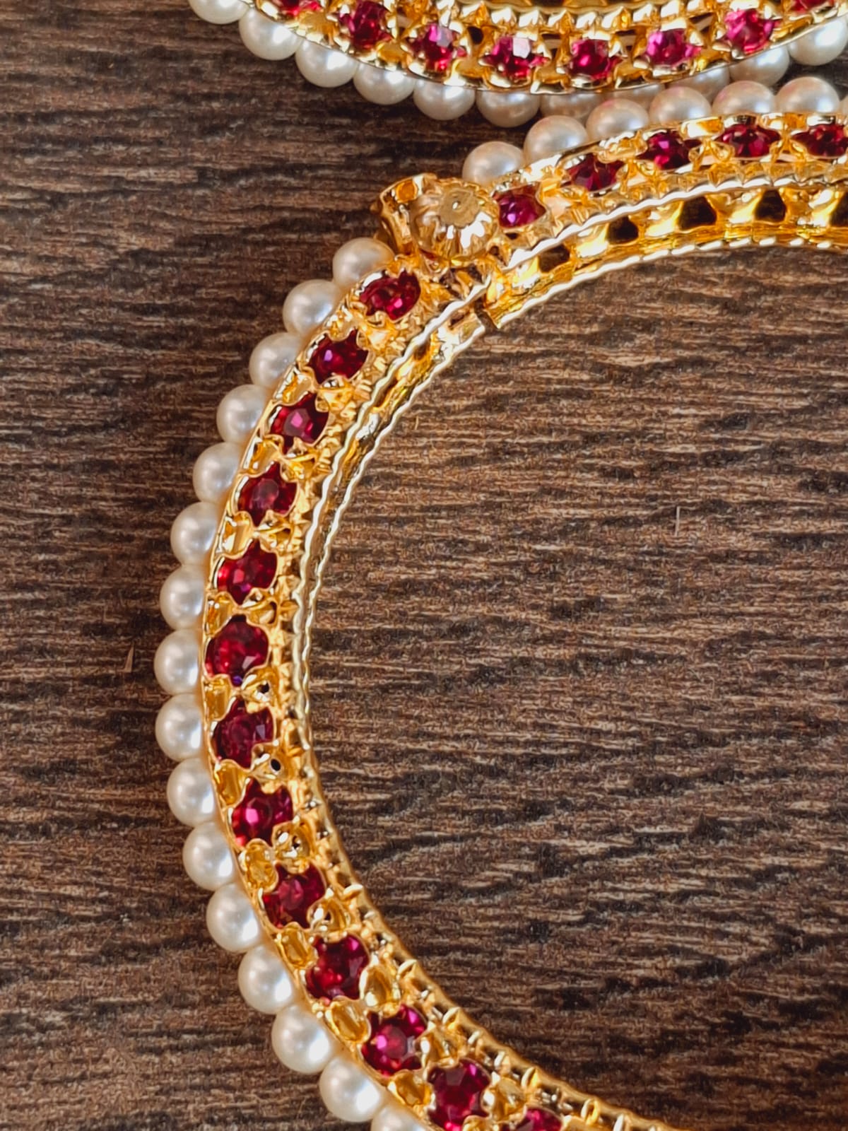 Traditional gold and pearl tode with red gemstones on wooden background.