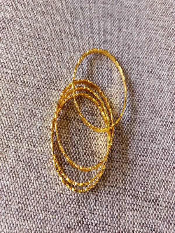 Stunning golden bangles set. Four interlinked oval-shaped bangles crafted from shiny metallic material, creating a dazzling and eye-catching accessory.