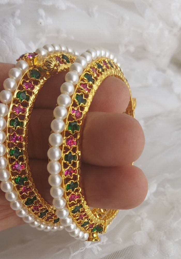 Pair of traditional multicolour pearl-embellished gold bangles from Mugdha Jewellery Store, featuring intricate gemstone patterns.