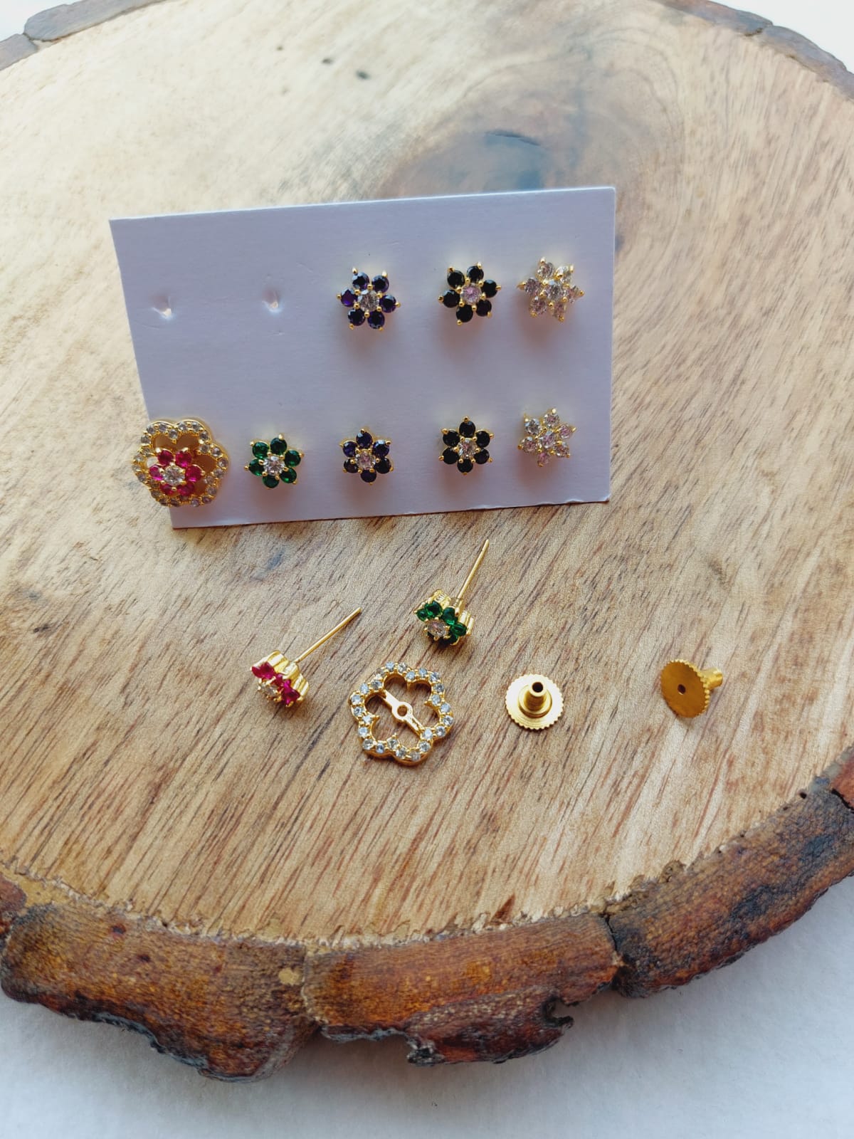 Flower Changeable Earrings 5 in 1 - Assorted colorful flower-shaped stud earrings on a wooden display, showcasing the versatile and interchangeable nature of this jewelry item from the Mugdha Jewellery Store.