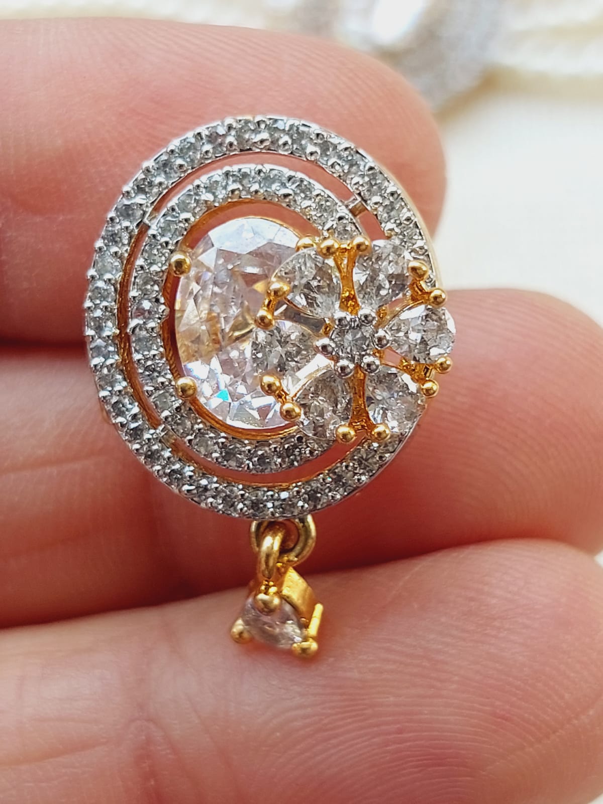 Elegant gold-tone diamond-encrusted flower-shaped pendant on display in the image