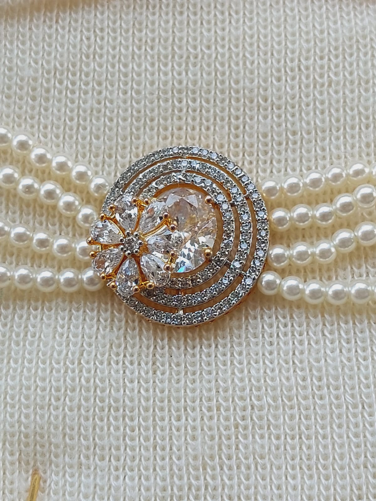 Elegant pearl necklace with a gold and diamond flower-shaped brooch centerpiece.
