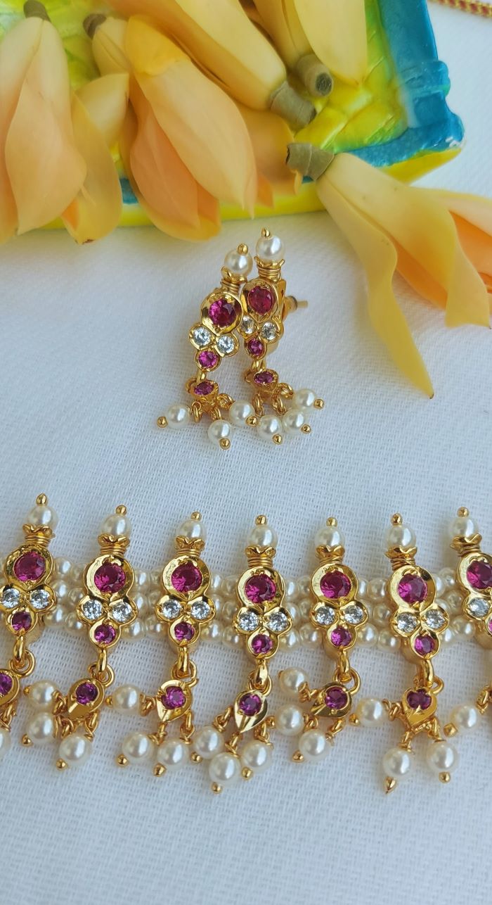 Elegant gold and ruby Indian jewelry set with floral and geometric patterns, surrounded by vibrant mango slices against a white background.