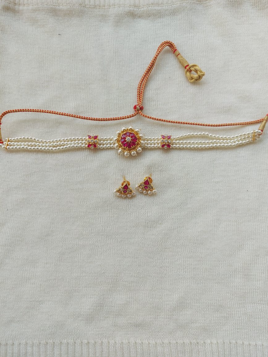Simple Elegant Pearl Choker necklace with floral motif and matching earrings, showcased on a neutral fabric background.
