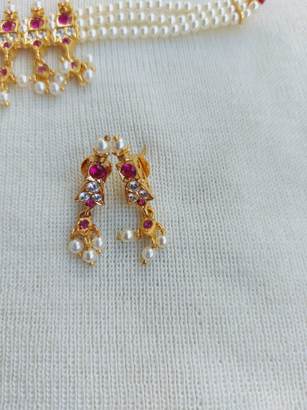 Gold-toned traditional Indian earrings with gemstones and pearls on a white background