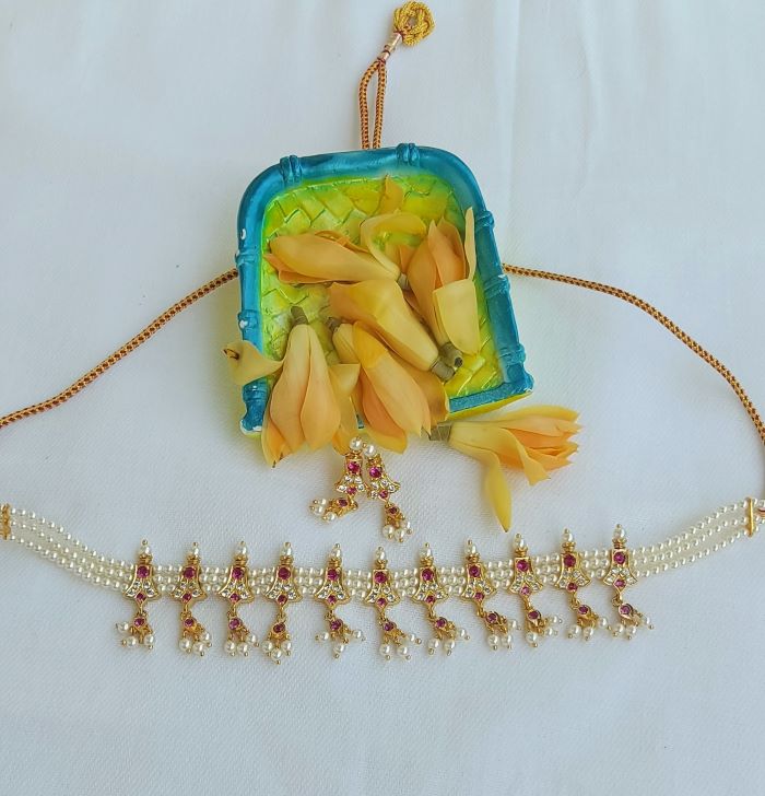Elegant pearl necklace with golden pendants showcasing a dark pink and green embellished chinchpeti design
