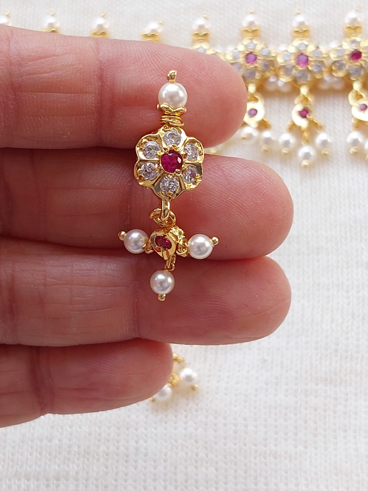 Elegant gold-tone flower pendant with sparkling rhinestones and pearls, showcased in hand.