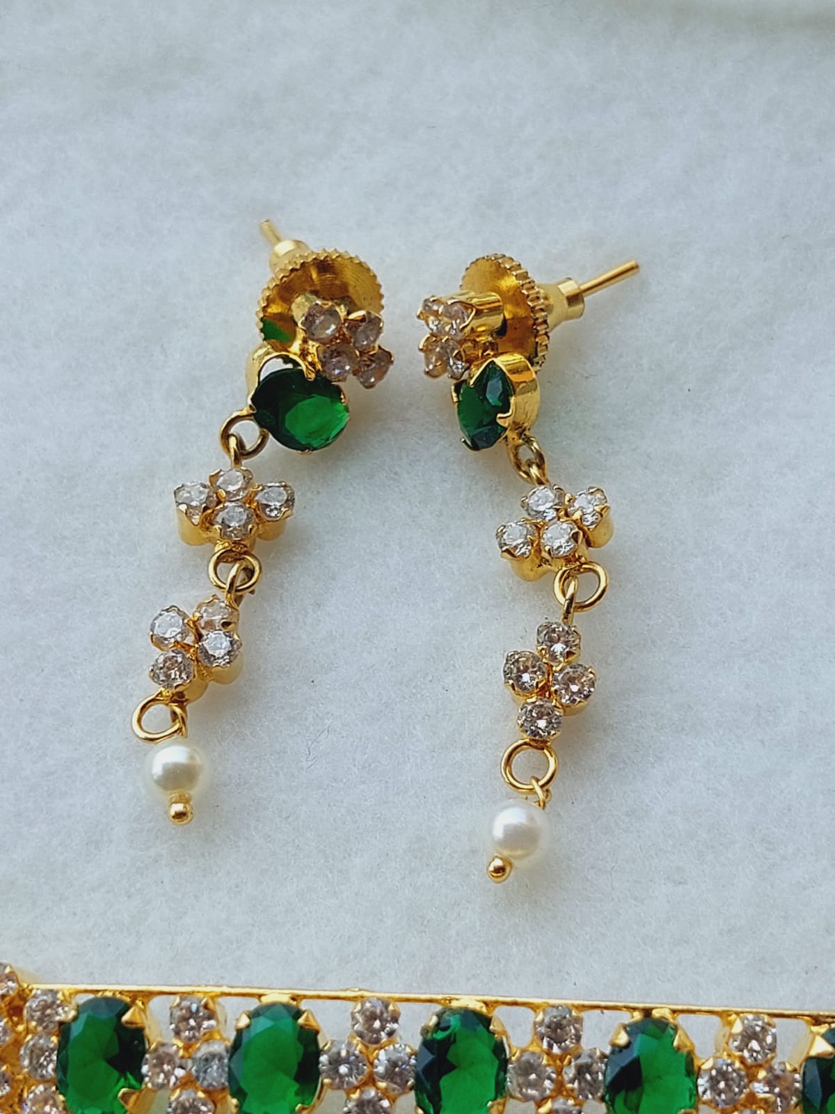 Elegant green, white, and golden designer choker featuring a flower-shaped arrangement of dazzling American diamonds on a gold-toned background.