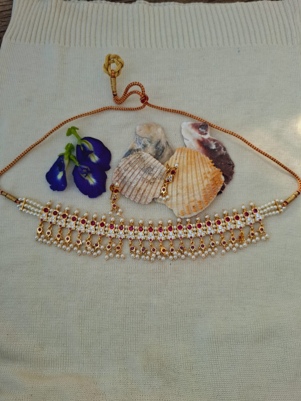 Regal gold-toned necklace with beaded accents and shells, showcased on a white background for Mugdha Jewellery Store.