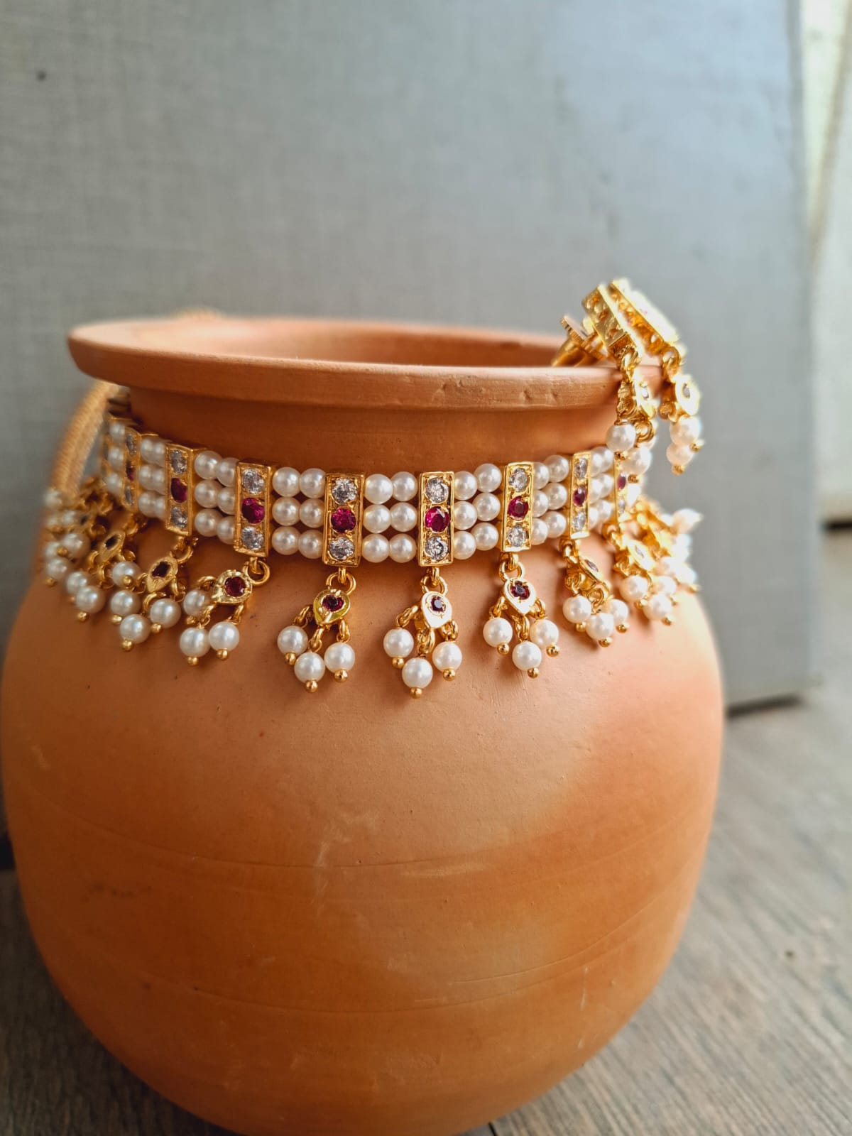 Ornate traditional necklace on earthenware pot from Mugdha Jewellery Store