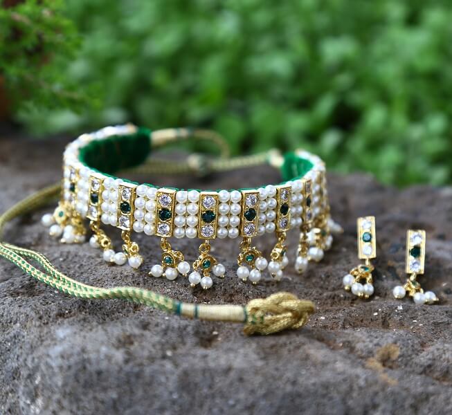 Ornate Green and White Stone Choker Necklace Set
This image shows an elaborate jewelry set consisting of a choker necklace, pendant, and earrings. The necklace features a green velvet band adorned with rows of white and green gemstones, as well as dangling pearl and gemstone accents. The pendant and earrings coordinate with the necklace's ornate design, creating a cohesive and high-end accessory set.