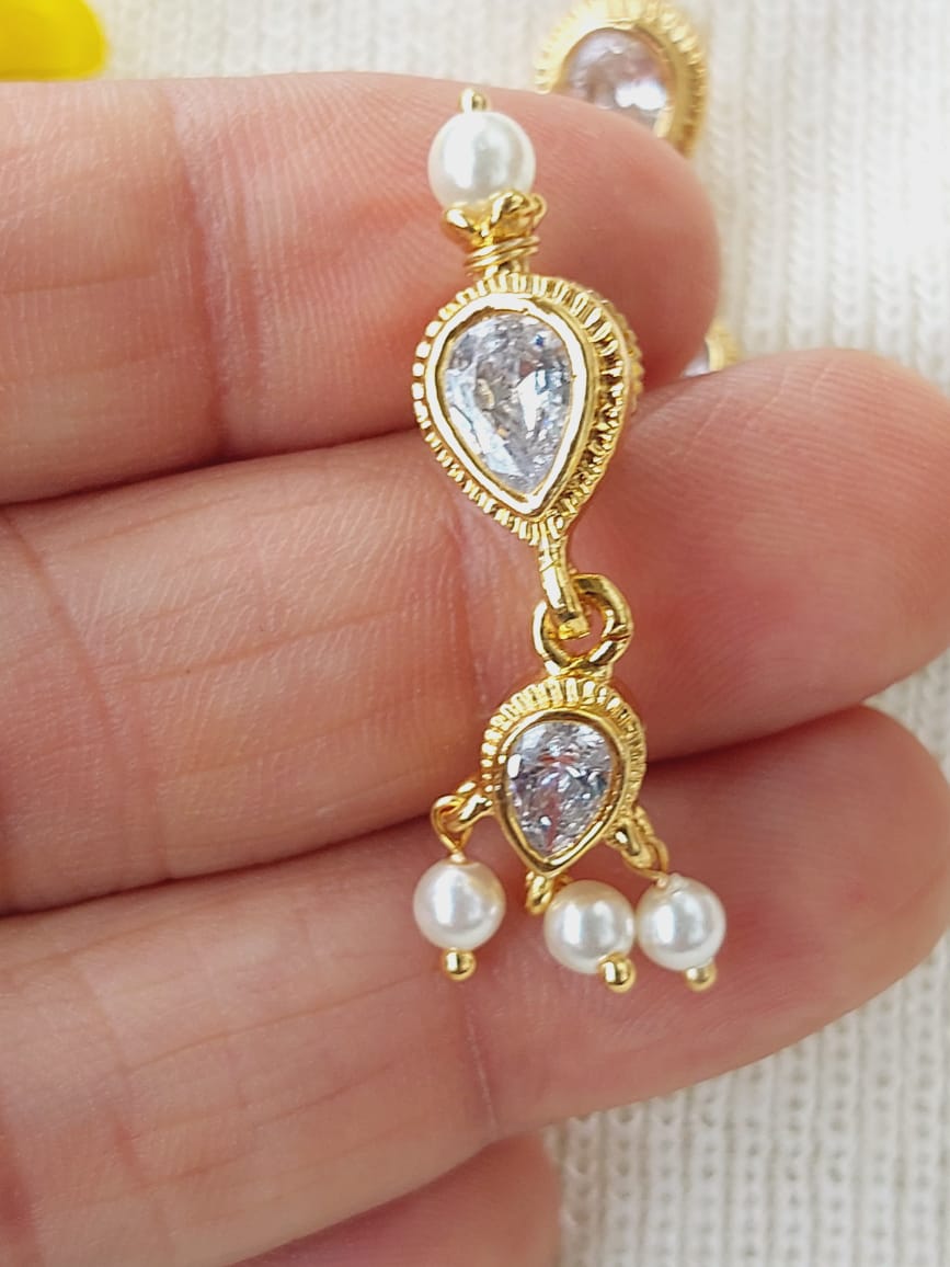 Elegant gold-tone tanmani earrings with sparkling crystal accents and delicate pearls, showcased on a hand.