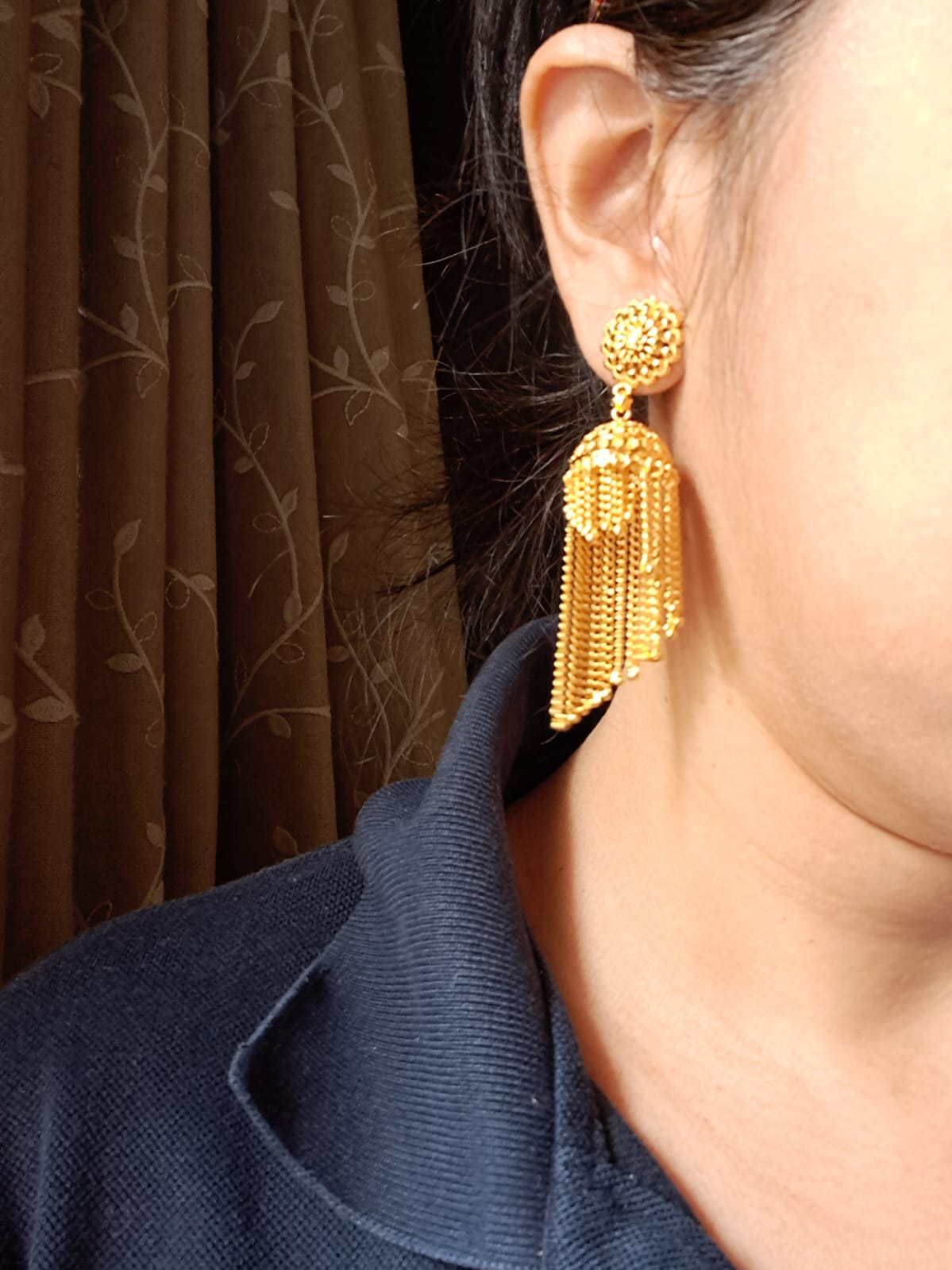 Elegant golden tassel earrings with intricate jewelry designs, showcased against a dark background.