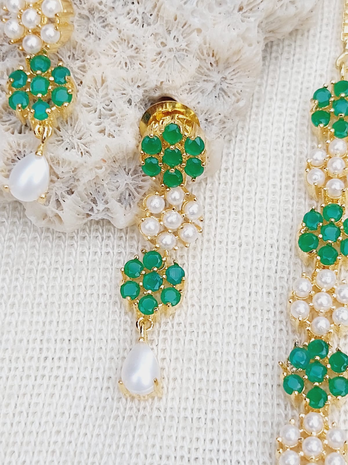 Green Stone Pearls Flower Necklace
Detailed image of a gold necklace with green gemstones and pearls arranged in a floral pattern, showcasing the intricate jewelry design.