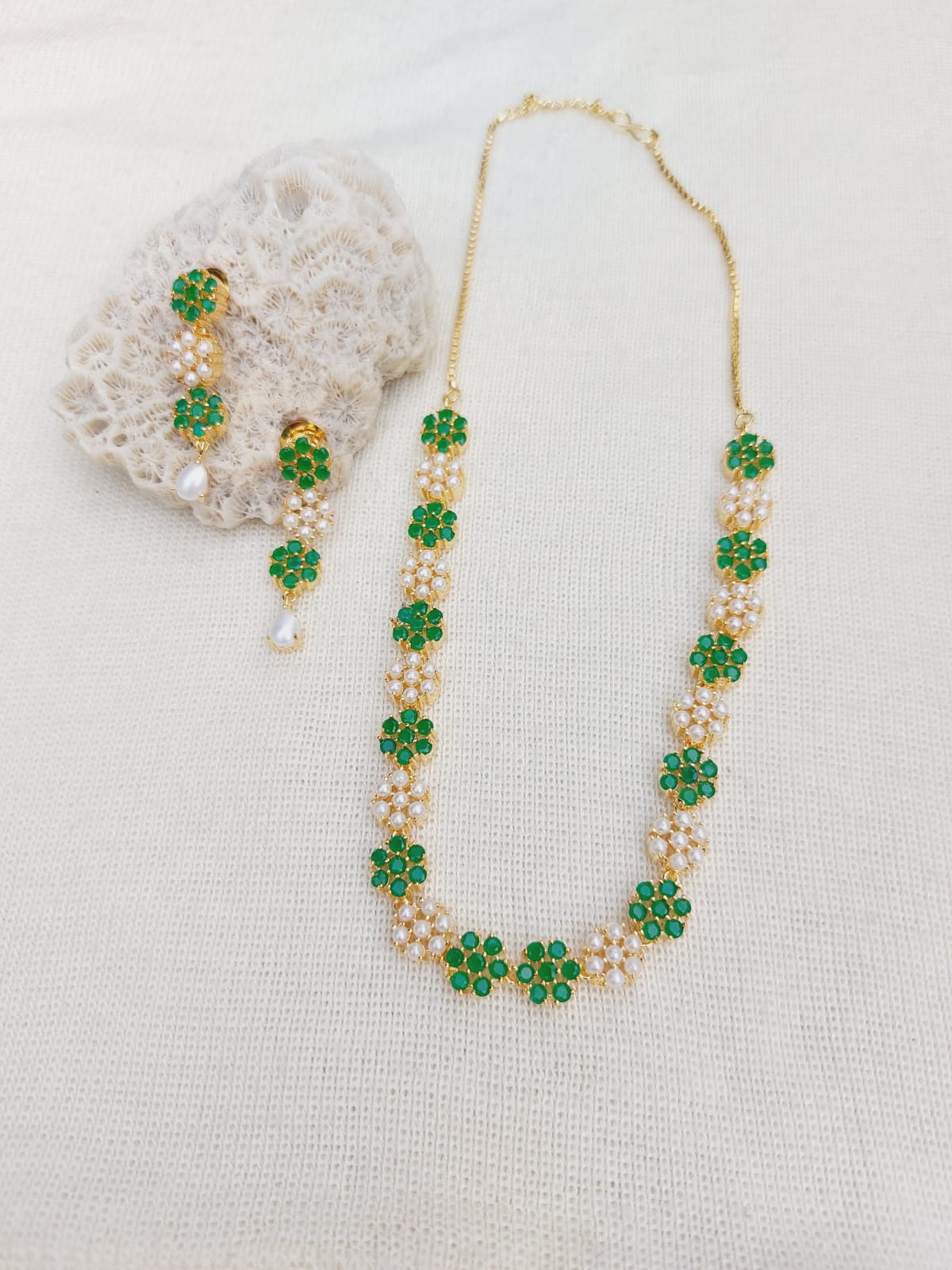 Elegant green stone and pearl flower necklace displayed on a white background