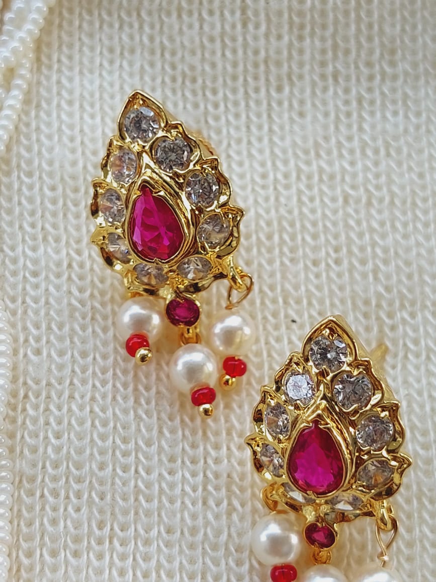 Elegant designer small pearl tanmani with ruby-colored gemstones and pearls, displayed on a white knitted fabric.