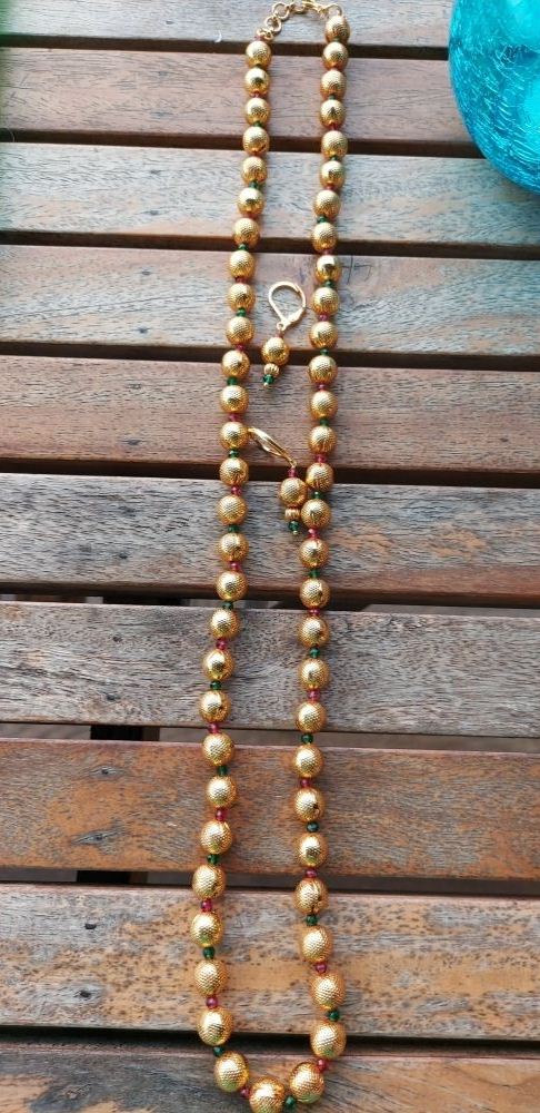 Elegant pearl necklace with golden accents displayed on a rustic wooden background.