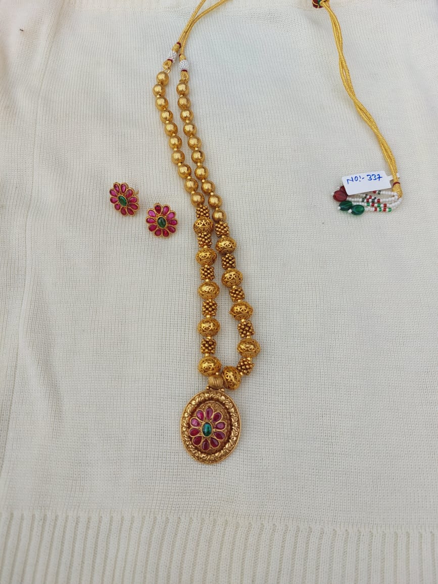 Golden beaded flower pendant necklace on white fabric background