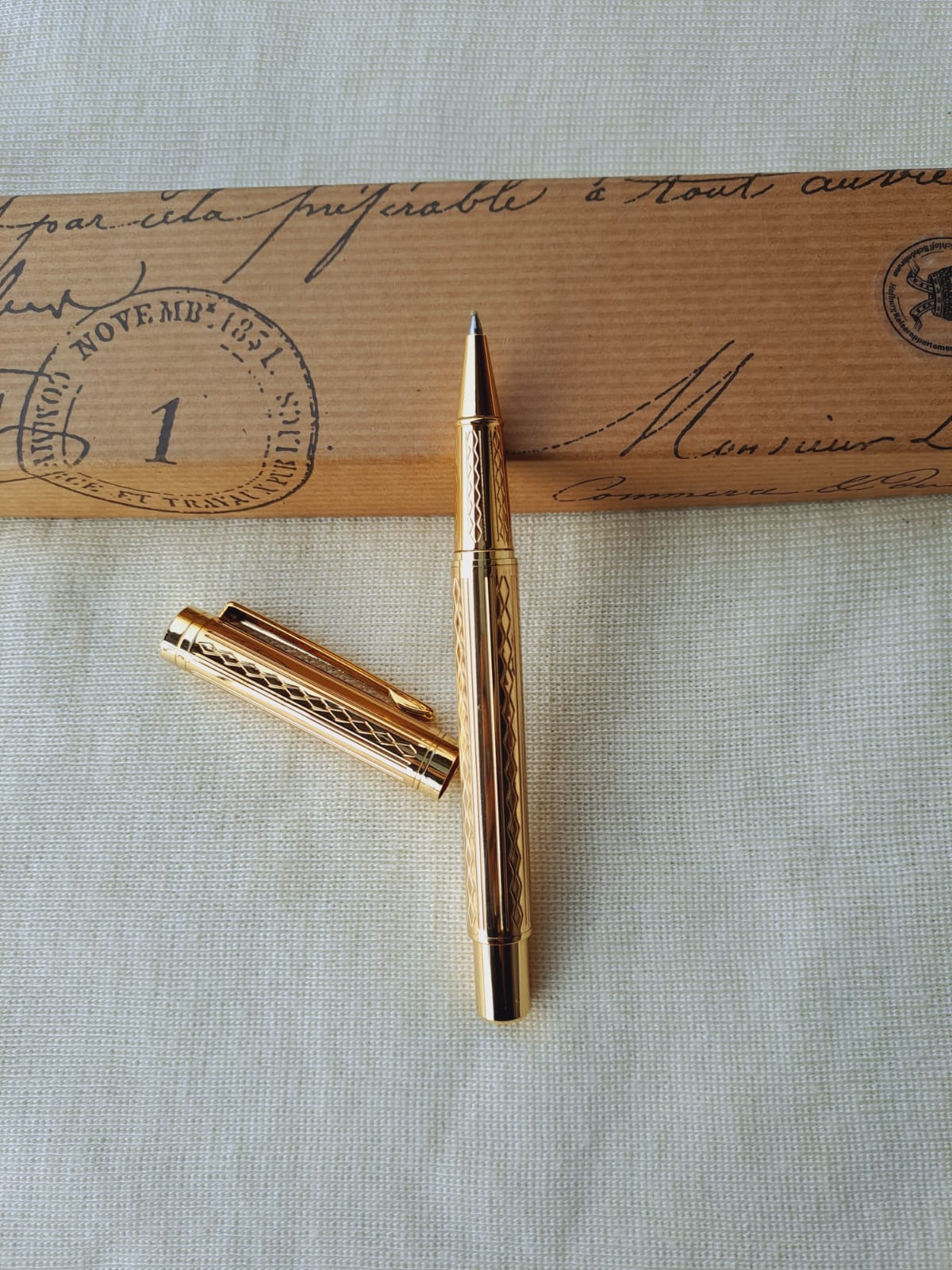 Elegant gold-toned designer pen on a vintage envelope with postage stamps, evoking an antique writing atmosphere.