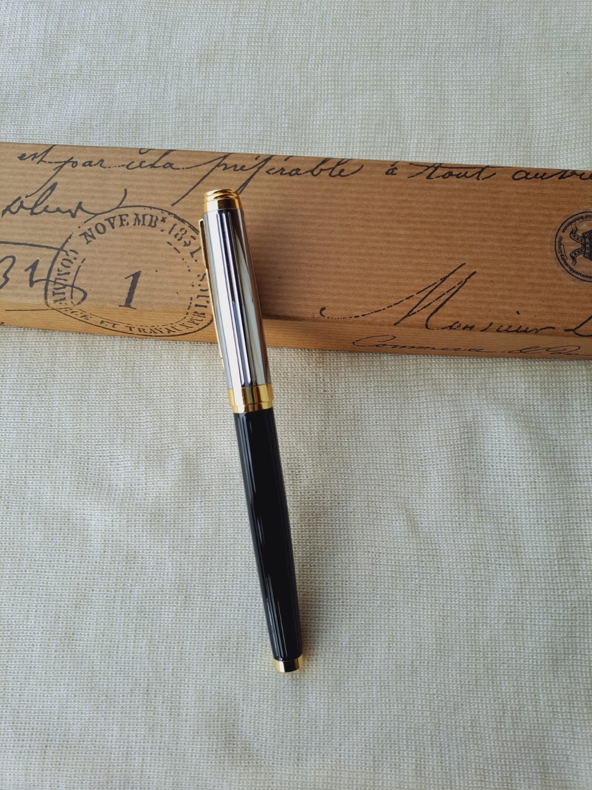 Elegant designer pen resting on antique envelope with handwritten address and postage stamp, showcasing a vintage aesthetic.