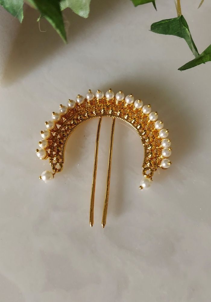 Golden Pearl Hair Accessory - Elegant hair clip adorned with sparkling golden pearls, displayed against a blurred nature background.