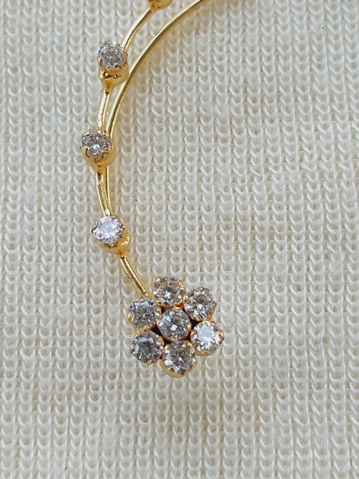 Elegant gold-tone earcuffs with delicate diamond-studded floral accents, displayed on a cozy knitted background.