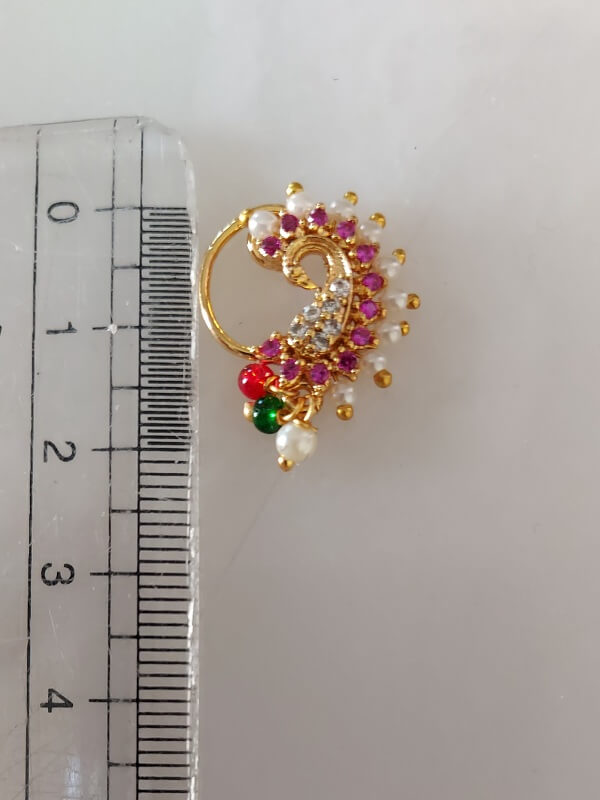 Elegant gold-toned peacock-shaped nath adorned with vibrant red, green, and yellow gemstones against a plain white background