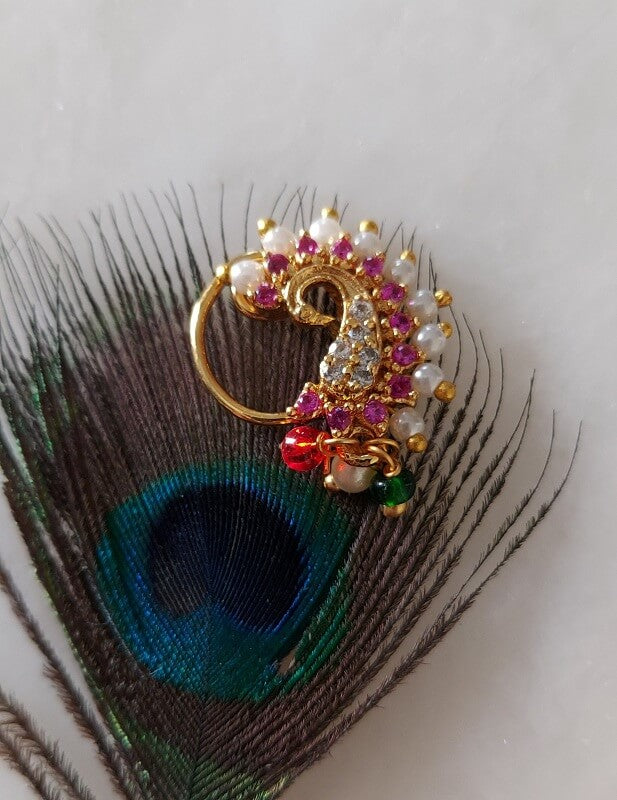 Ornate peacock nath adorned with sparkling jewels on a backdrop of vibrant peacock feathers