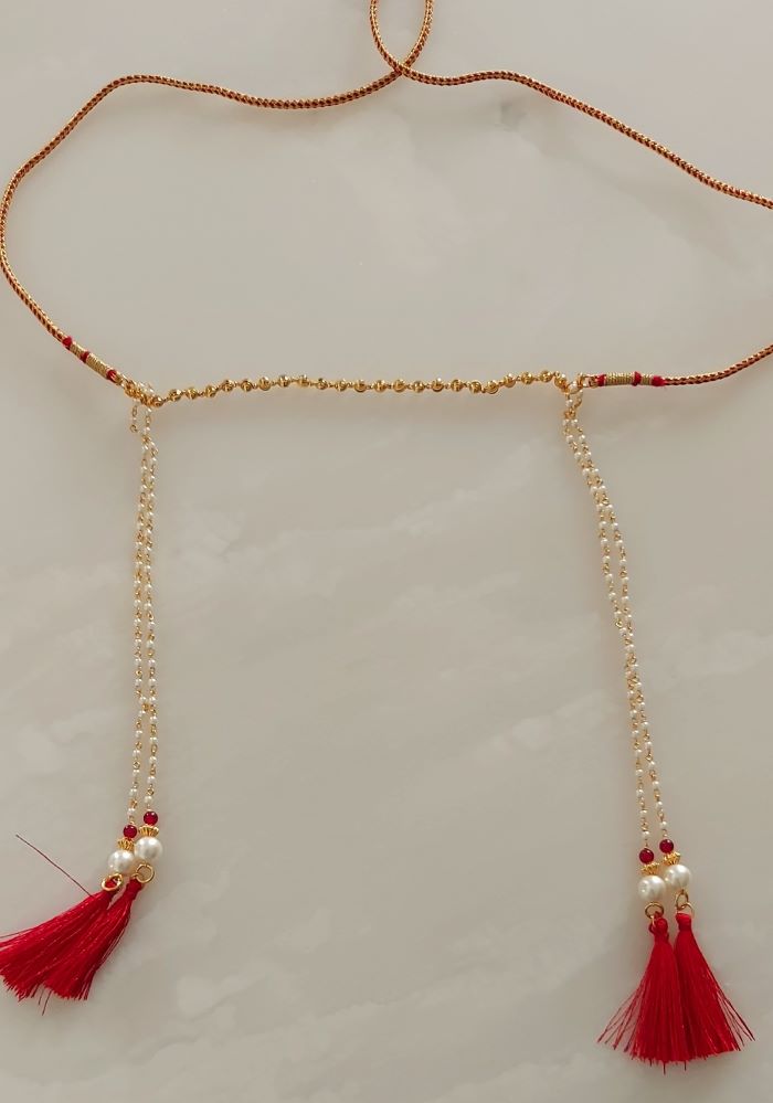 Decorative gold beaded necklace with red tassels, showcasing an elegant pendant design from Mugdha Jewellery Store.