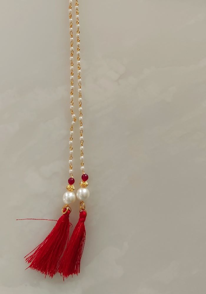 Elegant gold chain necklace with red tassels and pearl accents