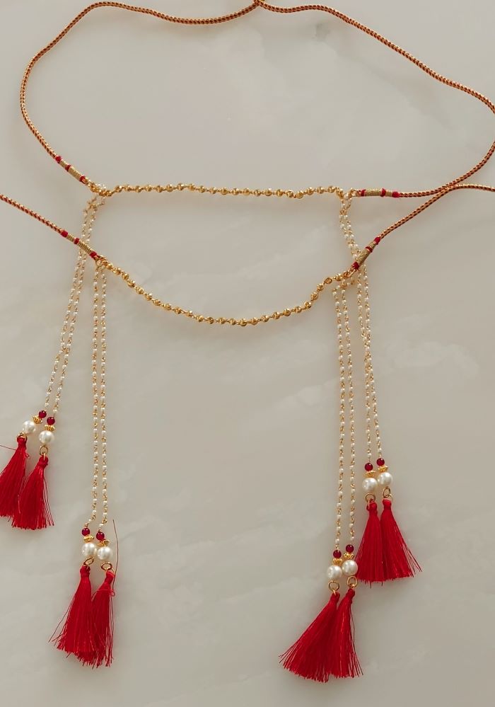 Elegant gold-toned necklace with red tassels and beads, showcasing intricate Mundavali 2 design from Mugdha Jewellery Store.