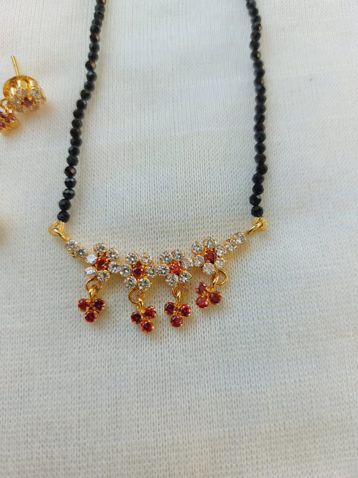 Ornate orange stone flower crystal mangalsutra with gold accents displayed on a white background.