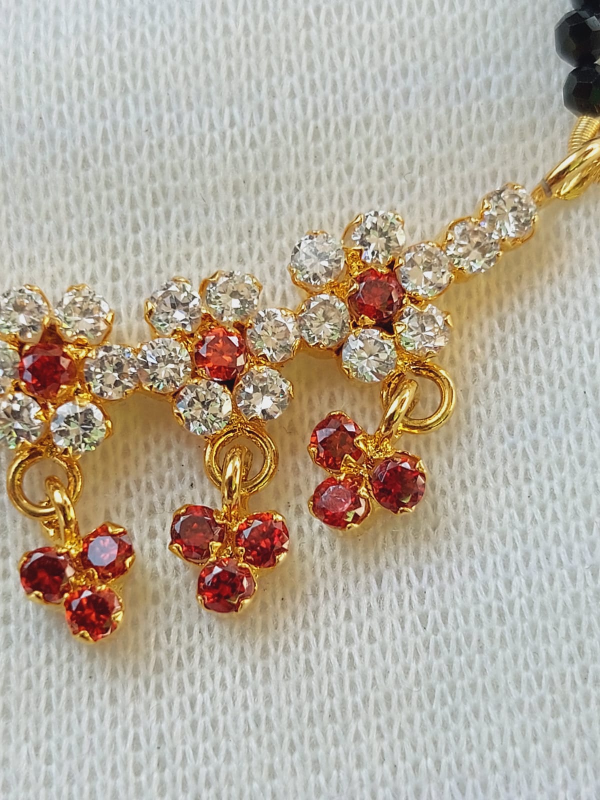 Orange Stone Flower Crystal Mangalsutra - Elegant gold-toned jewelry with vibrant orange and clear crystal stones arranged in flower designs.