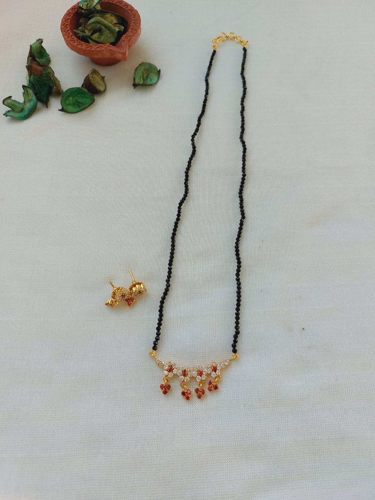 Orange Stone Flower Crystal Mangalsutra - Elegant gold-toned necklace with hanging orange stones and floral design, set against a white background.