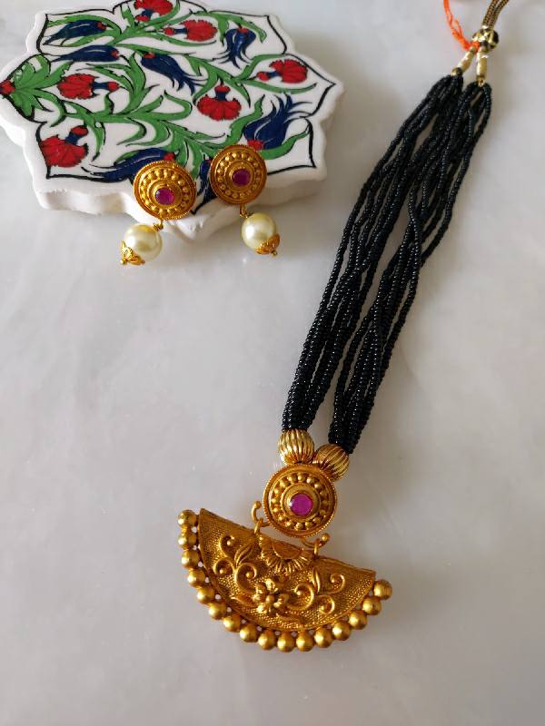Elegant gold and black half-circle mangalsutra pendant with colorful floral design, adorned with gold accents and beads, set against a white background.